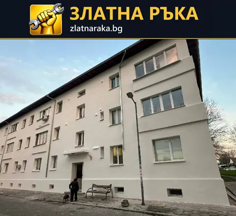 Дълга жилищна сграда със светла обновена фасада, бели прозорци и тъмни водосточни тръби
