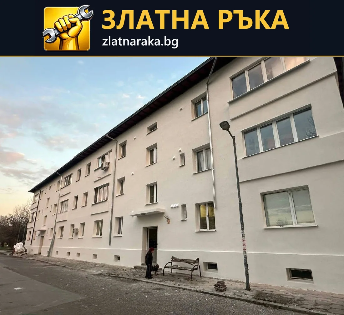 Дълга светлосива фасада на жилищна сграда с редици прозорци, тъмен цокъл и подчертан вход