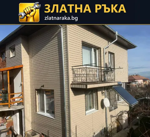 Двуетажна къща със светла хоризонтална фасадна облицовка, малък балкон и външни водосточни тръби
