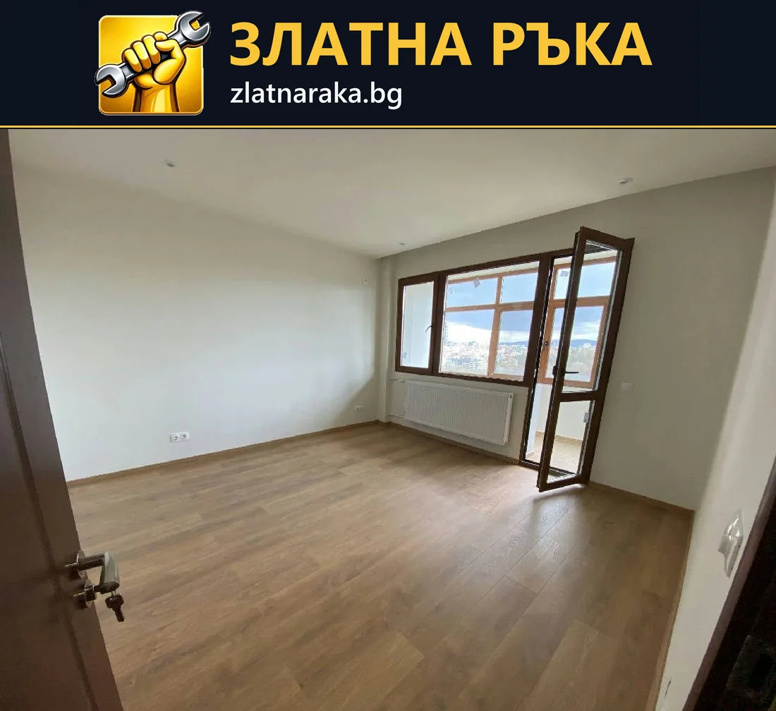 Празна стая със светли стени, дървесен под и кафява дограма с отворена балконска врата