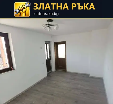 Светла стая със сив дървесен под и тъмна врата