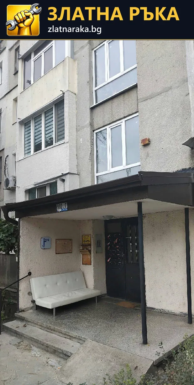 Тъмен метален навес над вход на жилищен блок с опорна колона пред вратата.