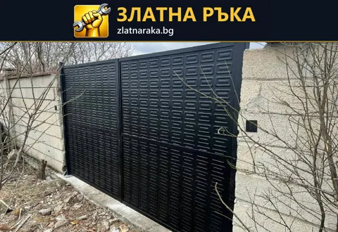 Двукрила тъмна метална порта с повтарящи се правоъгълни релефни полета