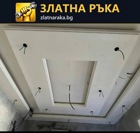 Незавършен бял таван с вложени правоъгълни рамки, кръгли отвори и висящи проводници