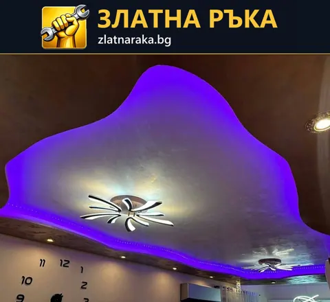 Таван с плавно извита светла централна форма и лилаво периферно осветление около декоративно осветително тяло