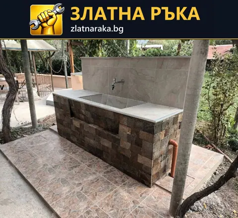 Дворна мивка с широк светъл плот, сив стенен гръб и основа с разноцветен каменен декор