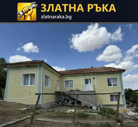 Къща с жълти хоризонтални фасадни панели и бели прозоречни рамки